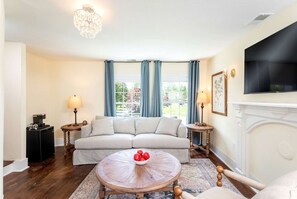 A living room with a sofa, a coffee table, a fireplace, and a television.