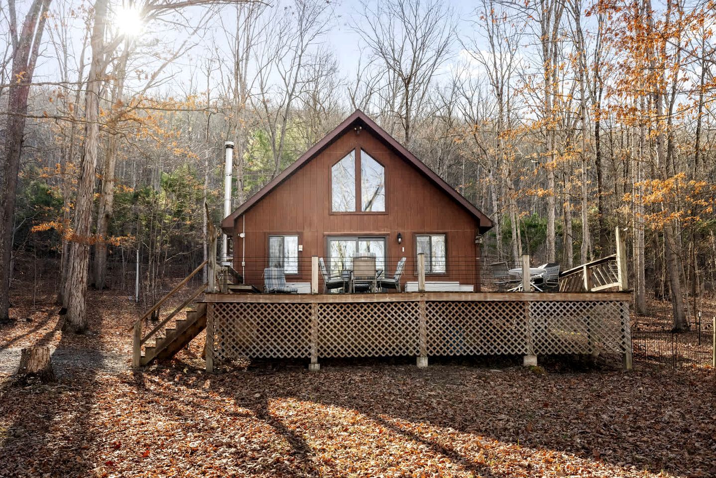 A cabin with a deck, surrounded by trees and a forest.