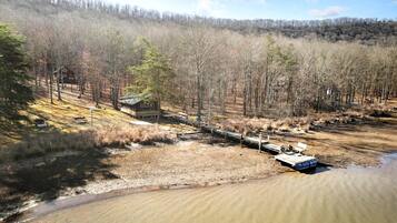A cabin in a forested area with a dock extending into a river.