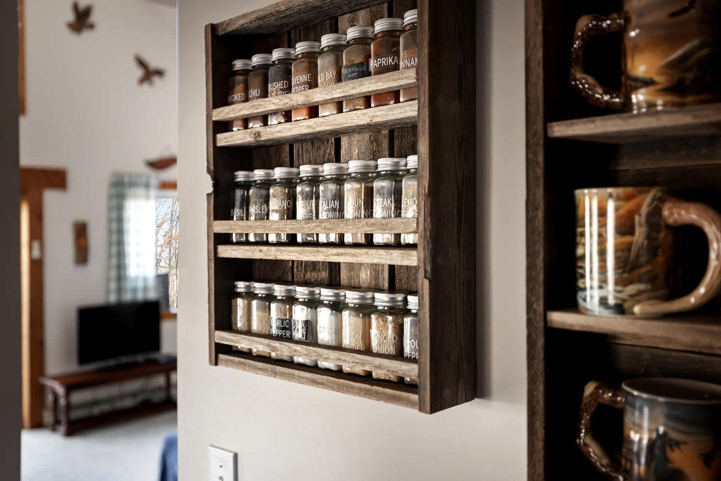 A wooden spice rack with jars labeled with various spices like smoked chili and basil.