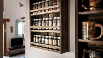 A wooden spice rack with jars labeled with various spices like smoked chili and basil.