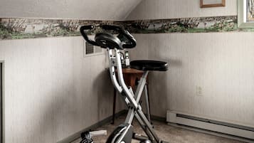 Ein stationäres Fahrrad steht in einer Ecke des Raumes, dessen Wand eine Struktur aufweist und ein Fenster zu sehen ist.