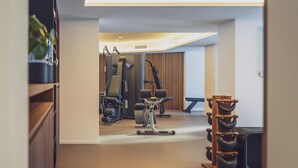 A modern home gym with exercise equipment, a treadmill, and a weight bench. - Hotel Joseph's House (Davos)
