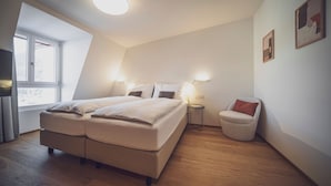 A bedroom with a bed, bedside tables, a chair, and a window. - Hotel Joseph's House (Davos)