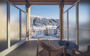 A balcony with a view of snow-covered mountains and a town below. - Hotel Joseph's House (Davos)