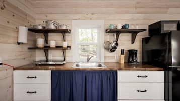 A kitchen with wooden walls, a sink, cabinets, and a window.