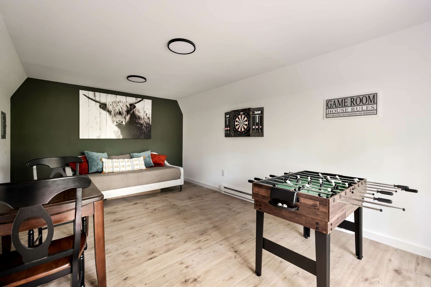 Ett rum med ett bordfotbollsspel, en darttavla, en soffa och en väggmonterad darttavla.