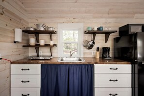 A kitchen with wooden walls, a sink, cabinets, and a window.