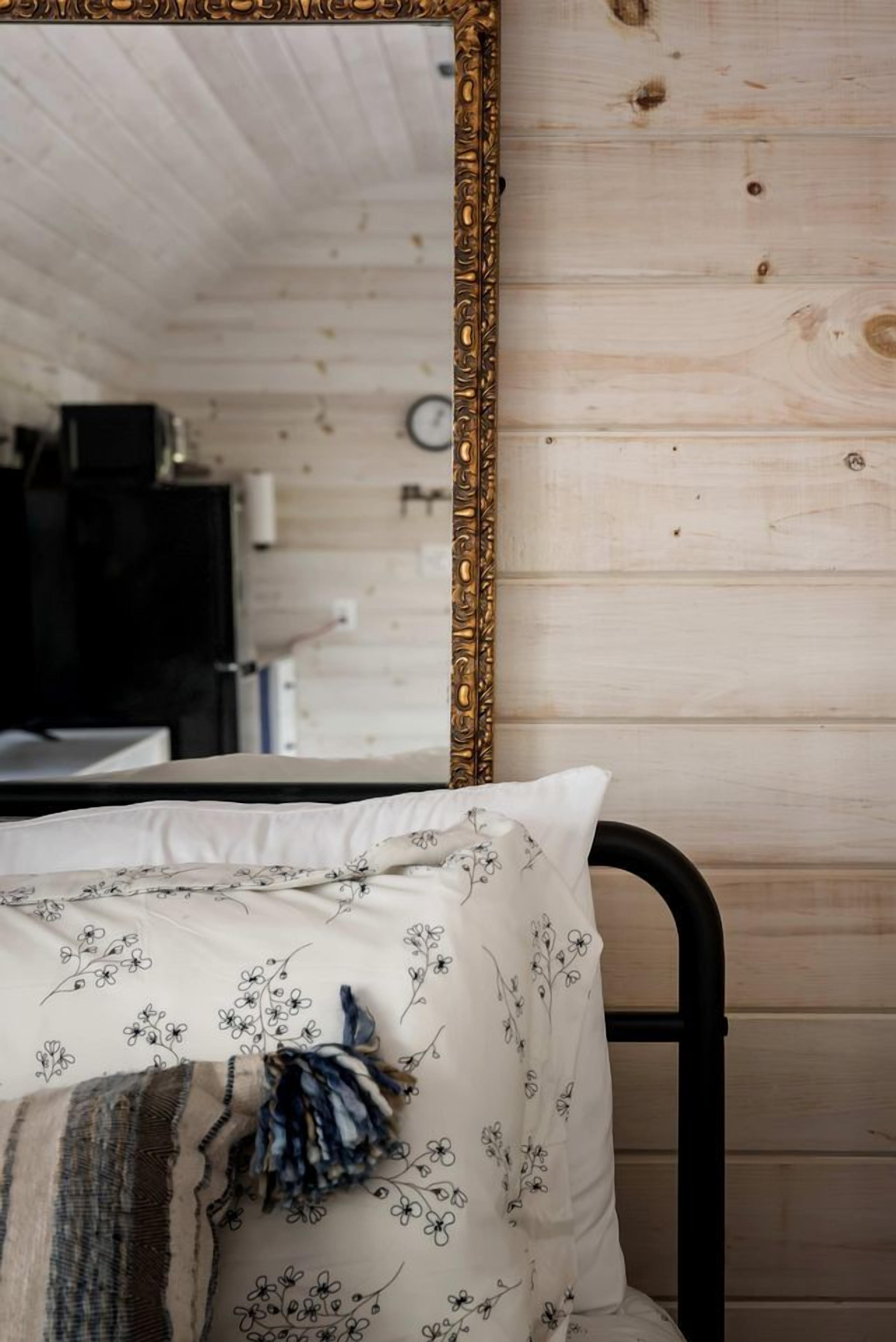 Een bed met een sierkussen met bloemenprint en een blauw-witte deken.