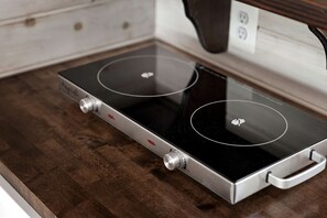 A modern induction cooktop with two control knobs and a sleek handle.