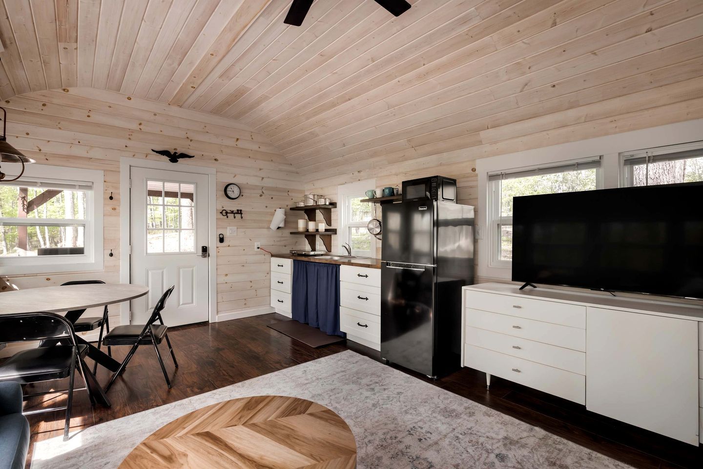A modern kitchen with a large refrigerator, microwave, and a flat-screen TV.