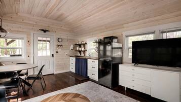 A modern kitchen with a large refrigerator, microwave, and a flat-screen TV.