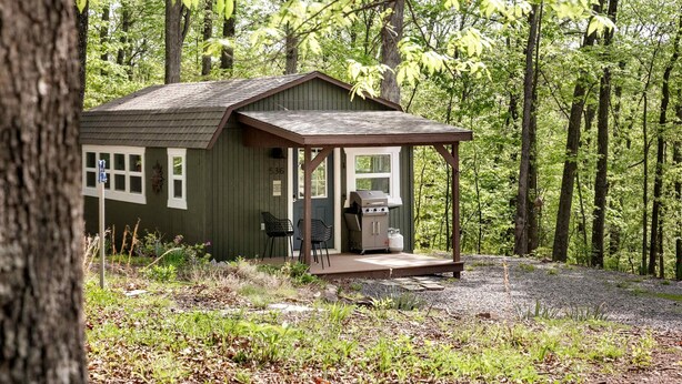 A cabin with a porch, a grill, and a number '536' on the door. - Modern Tiny Cabin with Game Room & Fire Pit in West Virginia (Great Cacapon)