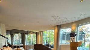 Moderni olohuone, jossa on suuri kulmasohva, persoonallinen nojatuoli ja suuret ikkunat, joista avautuu näkymä ulos.