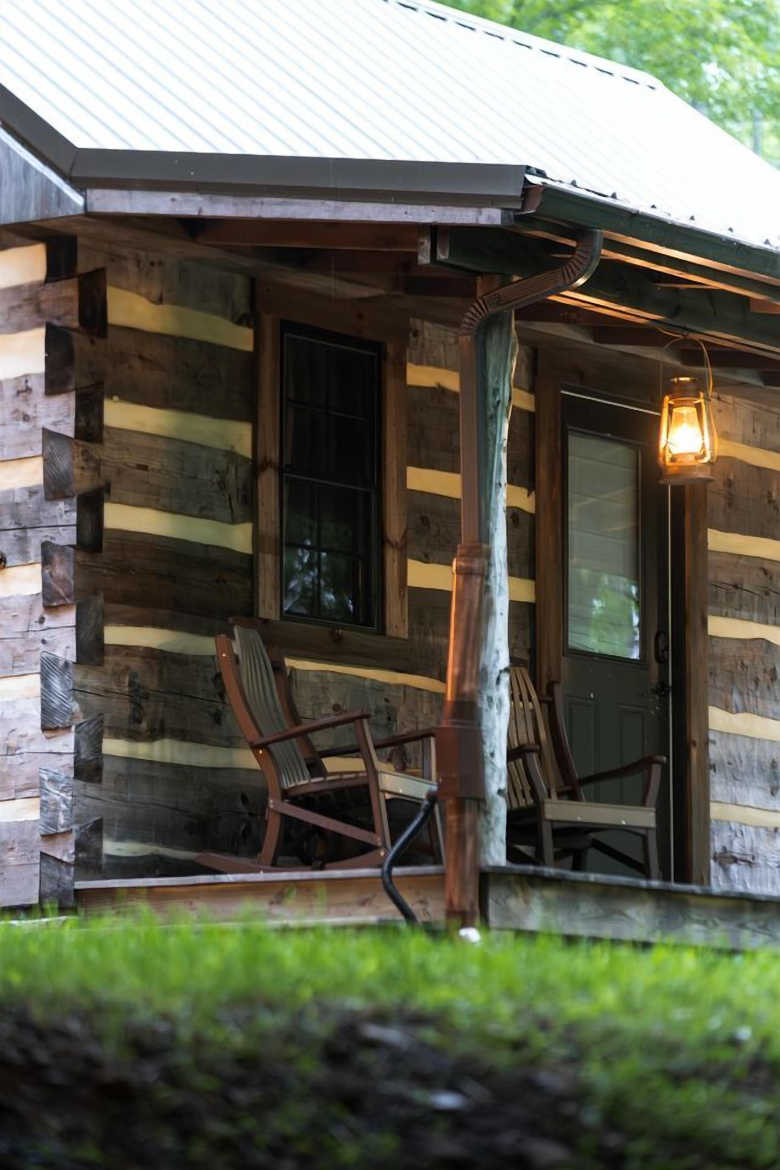 A log cabin with a porch, two rocking chairs, and a lantern.