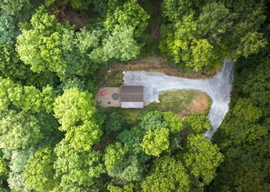 An aerial view of a property with a house, a paved driveway, and a small patio area with outdoor furniture.