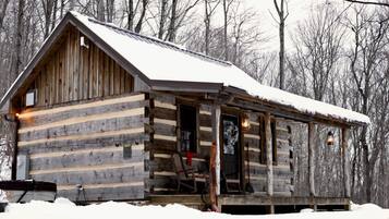 Une cabane en rondins avec une véranda, une porte et une fenêtre.