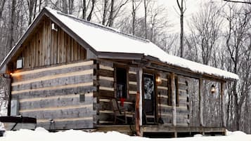 Eine Blockhütte mit Veranda, einer Tür und einem Fenster.
