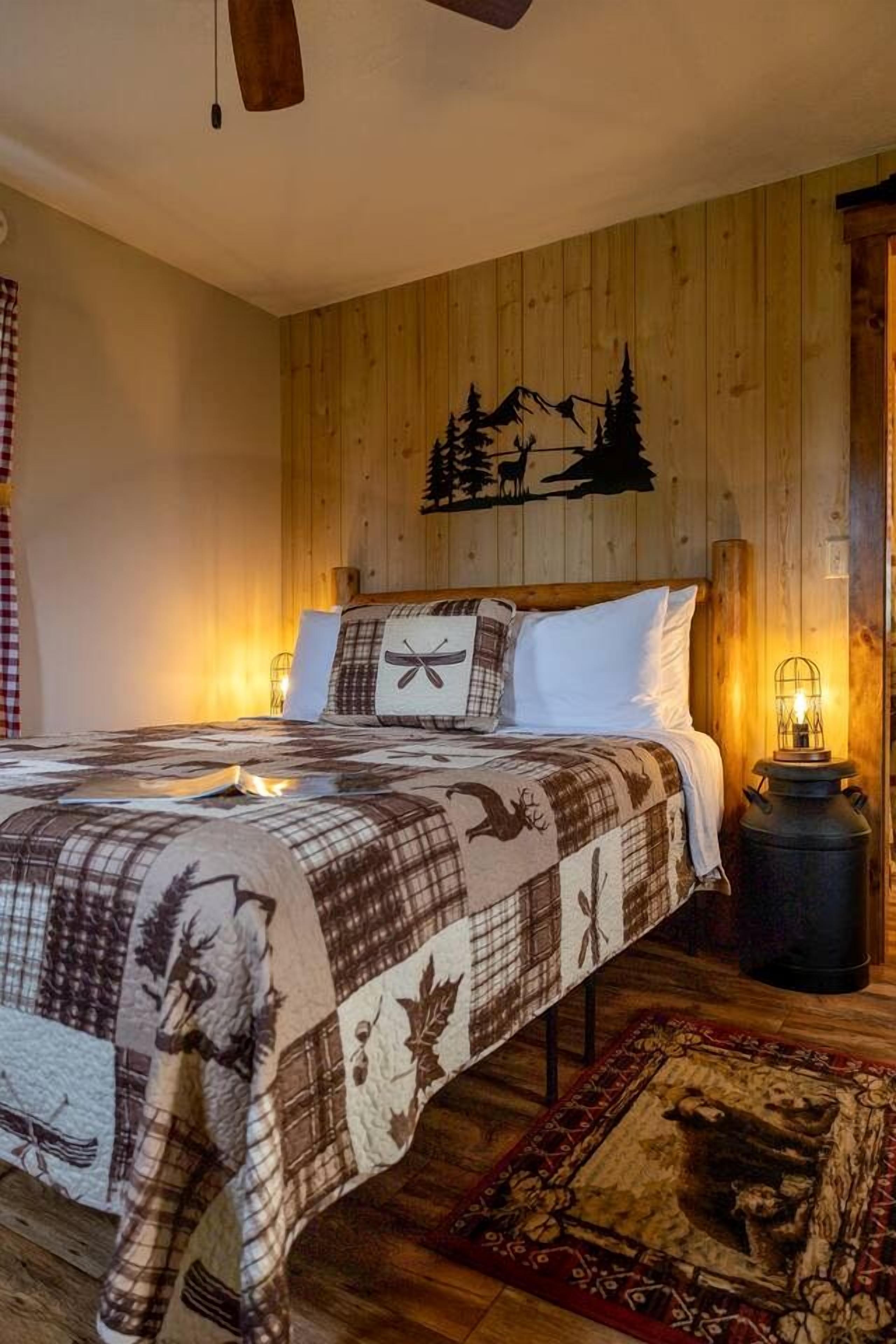 A wooden-paneled bedroom with a bed, a nightstand, and a wall-mounted lamp.
