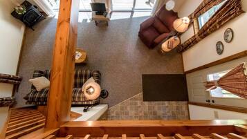 Ein modernes Interieur mit Treppe, einer Couch, einem Sessel, einem kleinen Tisch und einem Fenster mit Vorhängen.