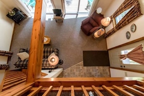 Ein modernes Interieur mit Treppe, einer Couch, einem Sessel, einem kleinen Tisch und einem Fenster mit Vorhängen.