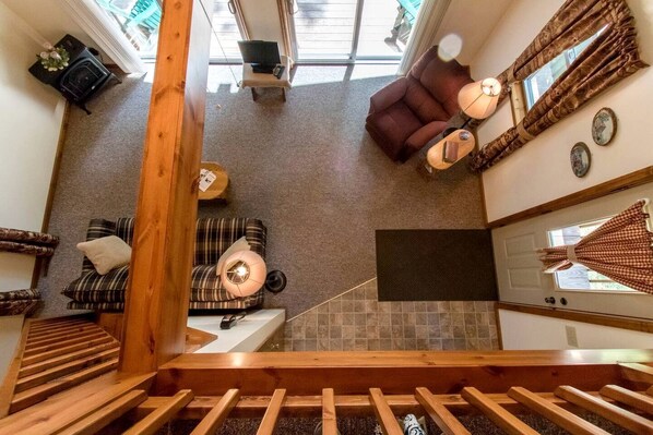 A modern interior with a staircase, a sofa, a chair, a small table, and a window with curtains. - Secluded West Virginia Cabin Rental on the Edge of Monongahela National Forest (Riverton)