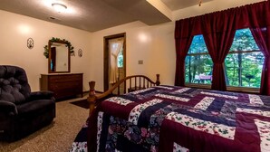 A bedroom with a bed, a chair, a dresser, a mirror, and a window with curtains. - Secluded West Virginia Cabin Rental on the Edge of Monongahela National Forest (Riverton)