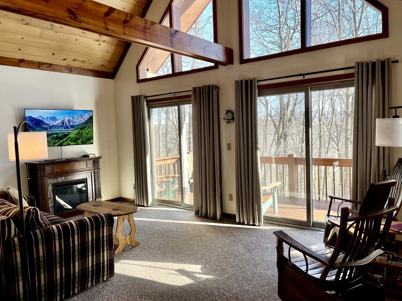 A cozy living room with a fireplace, a television, and a view of the outdoors.