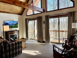 A cozy living room with a fireplace, a television, and a view of the outdoors. - Secluded West Virginia Cabin Rental on the Edge of Monongahela National Forest (Riverton)