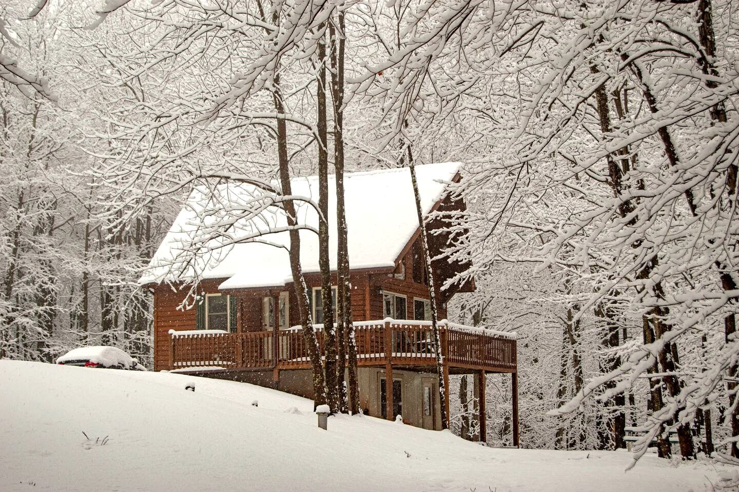 A cabin with a wooden exterior, a porch, and a snow-covered roof.