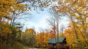 A cabin surrounded by autumn foliage, a gravel path leading to it, and a clear sky. - Secluded West Virginia Cabin Rental on the Edge of Monongahela National Forest (Riverton)