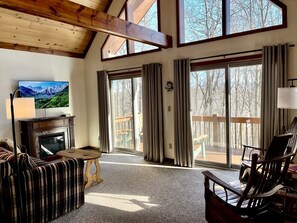 A cozy living room with a fireplace, a television, and a view of the outdoors.
