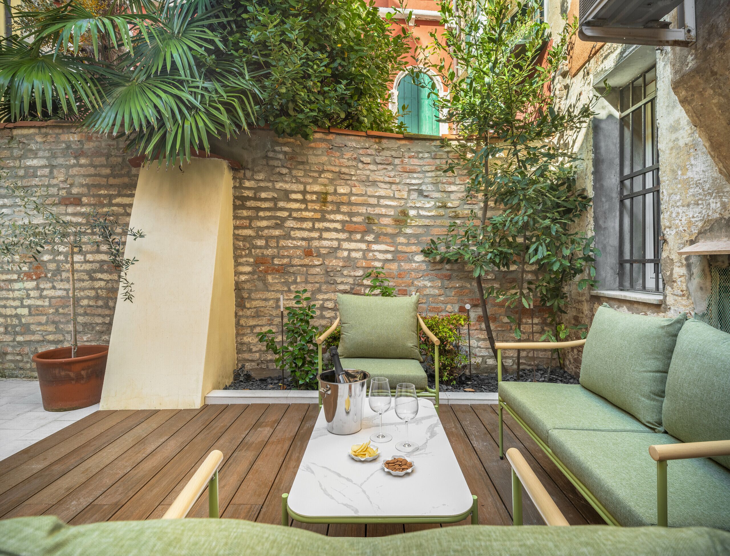 A cozy outdoor seating area with a wooden deck, a white table, and green cushioned chairs.