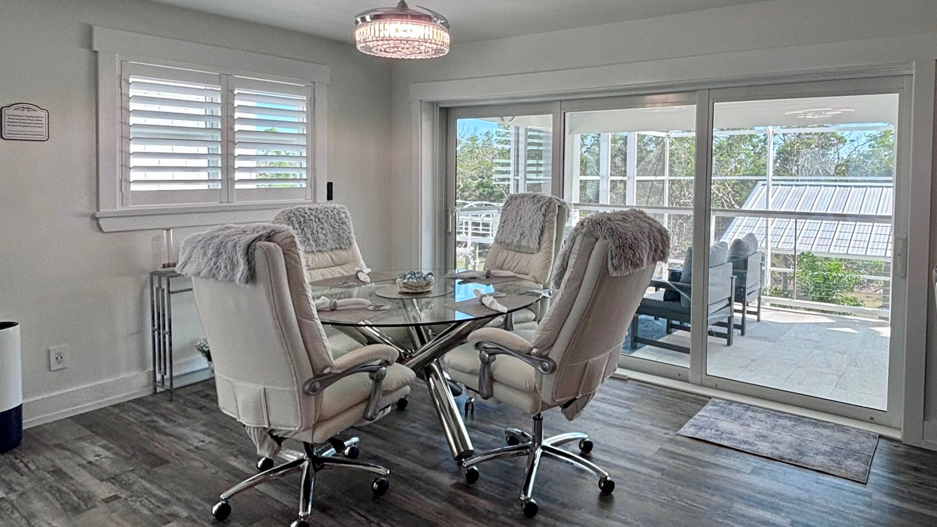 A conference room with a glass table and four chairs, large windows, and a chandelier.