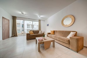 Un salon spacieux avec deux canapés, une table basse et une grande fenêtre donnant sur un immeuble.
