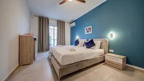 Un dormitorio con cama, mesitas de noche, ventilador de techo y vistas al exterior.