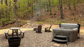 Un camping con una mesa de picnic, dos sillas Adirondack, un brasero y un calentador portátil.