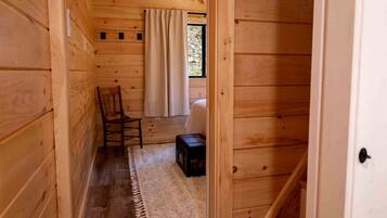 A narrow wooden hallway with a chair, a small rug, and a suitcase.