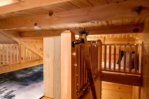 A wooden interior with a staircase, a bed with pillows, and a small plant.