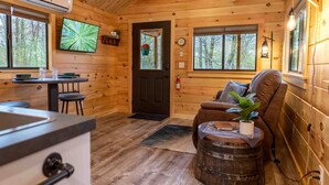 Een houten chalet van binnen, met een keuken, een eethoek en een zithoek.