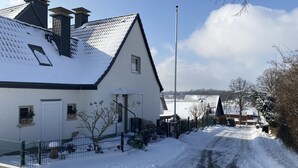 Une rue résidentielle enneigée, bordée de maisons, avec un ciel dégagé et une chaussée bien visible.