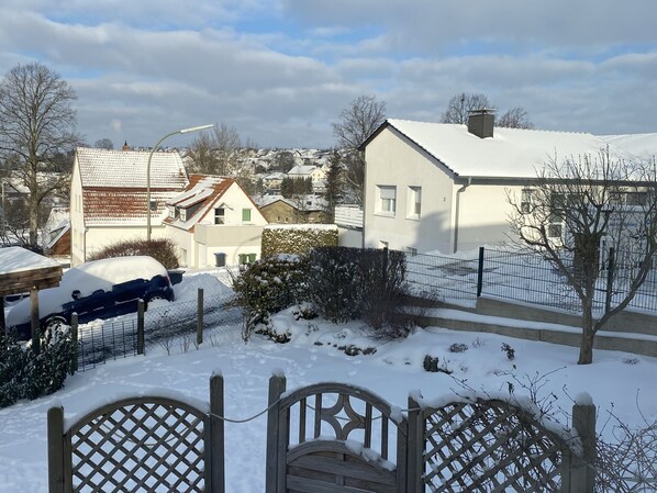 Un quartier résidentiel avec des maisons, une voiture recouverte de neige et un portail en bois.