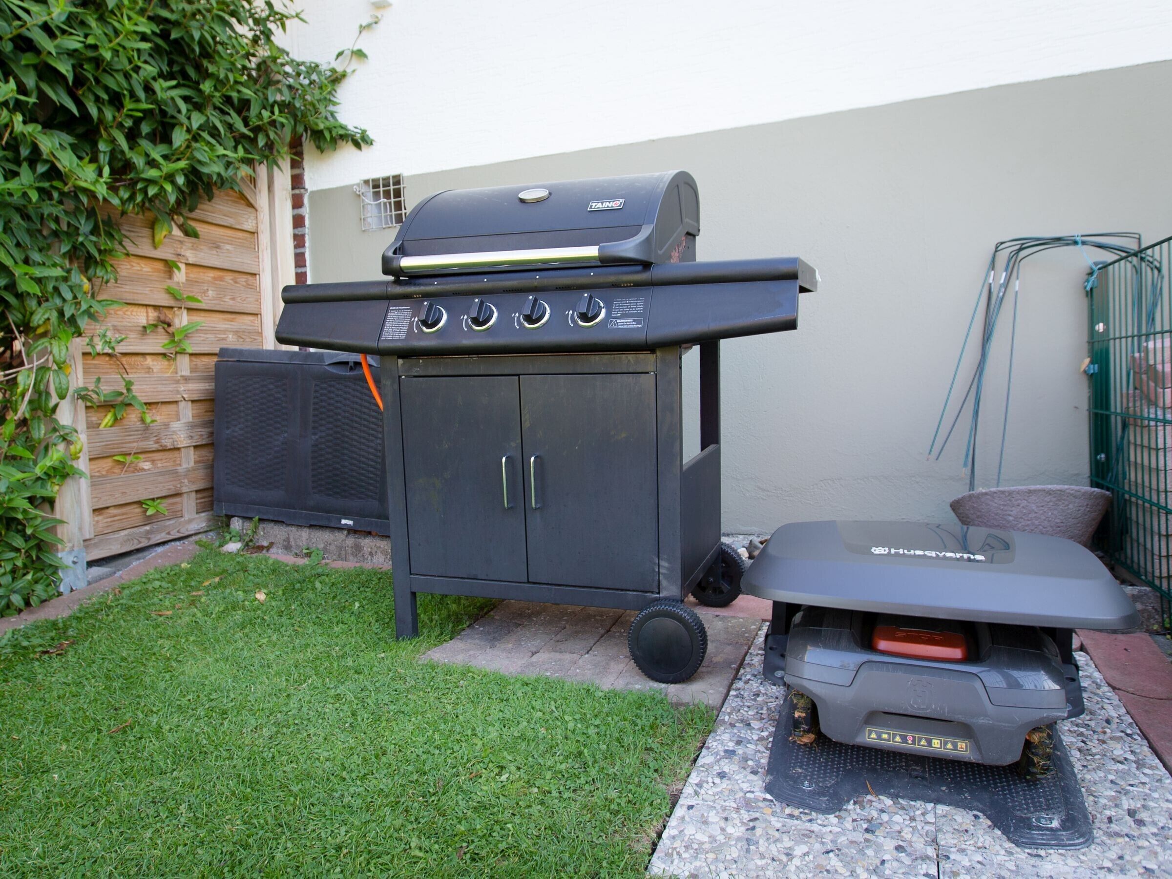 Un barbecue doté de quatre brûleurs, d’un meuble latéral et d’un chariot à roulettes pour le barbecue.