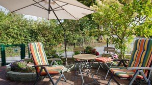 Une terrasse extérieure avec une table, des chaises et un grand parasol.