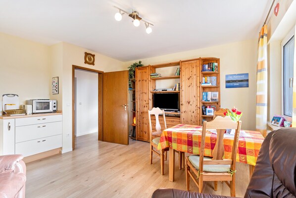A compact living space with a kitchenette, dining area, and a TV.