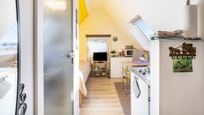 A narrow hallway with a bed, a desk, a television, and a window. - Studio Casa Felicitas, 1 living/sleeping room, max. 2 guests (not suitable for young children or dogs) (Möhnesee)