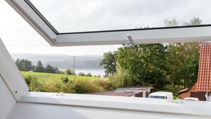 A skylight window with a view of a lake, trees, and a building with a red roof. - Studio Casa Felicitas, 1 living/sleeping room, max. 2 guests (not suitable for young children or dogs) (Möhnesee)
