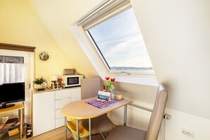 Una kitchenette compacta con microondas, una mesita con camino de mesa, una silla y ventana con vistas.