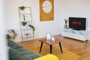 A living room with a sofa, a coffee table, a TV, a bookshelf, and a wall clock. - City of Rastatt—Stylish Living in a Historic Building (Rastatt)