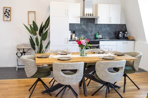 A modern dining area with a wooden table set for six, surrounded by upholstered chairs with cut-out backs. - City of Rastatt—Stylish Living in a Historic Building (Rastatt)